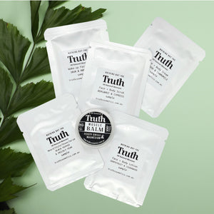 Truth Cosmetics vegan skincare sample pack with white sachets and muscle balm tin on green leaves