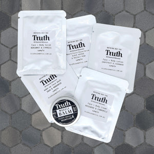Truth Cosmetics vegan skincare sample pack of sachets and small balm tin on gray hex tile background